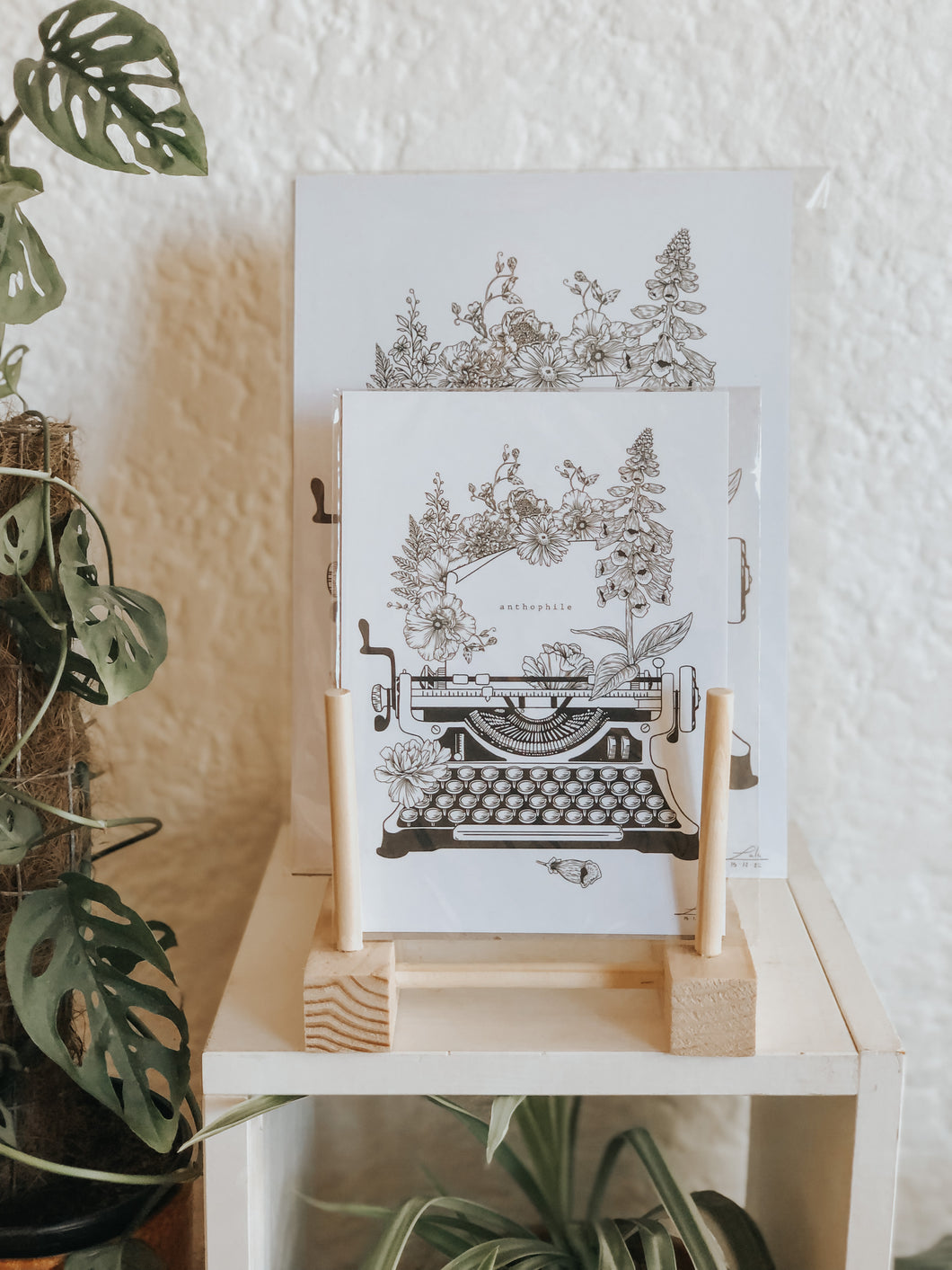 Black and white illustration of a typewriter surrounded with botanicals. The message reads 