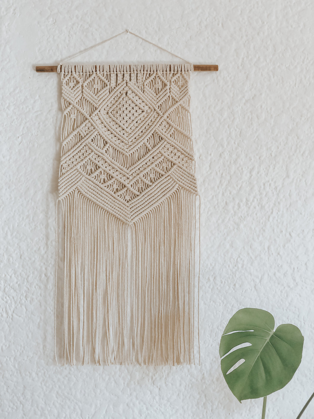This hanging has a beautifully complex yet simple design, using diagonal double half hitch knots to create texture. Made with natural 3mm cotton rope on a wooden dowel rod.