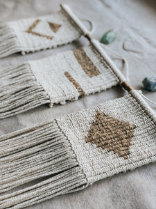 These simple geometric shapes (triangle, stripes and diamond) add a modern touch to your space. They are made using vertical double half hitch knots which allow me to play with pixel art in fibre form. Made with natural 3mm cotton rope and jute twine on a wooden dowel rod.