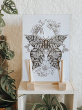 Black and white illustration of a moth with fern wings, surrounded by botanicals. Pair your prints with other illustrations to create a whimsical story of your own.