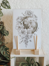 Black and white illustration of the Moon surrounded with botanicals. Pair your prints with other illustrations to create a whimsical story of your own.