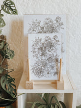 Black and white illustration of a skeleton intricately surrounded with botanicals. Pair your prints with other illustrations to create a whimsical story of your own.