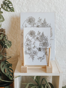 Black and white illustration of botanicals, hexagons and a sweet little bee. Pair your prints with other illustrations to create a whimsical story of your own.